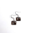 Square-shaped earrings with black and white, sometimes redish, design on a white background