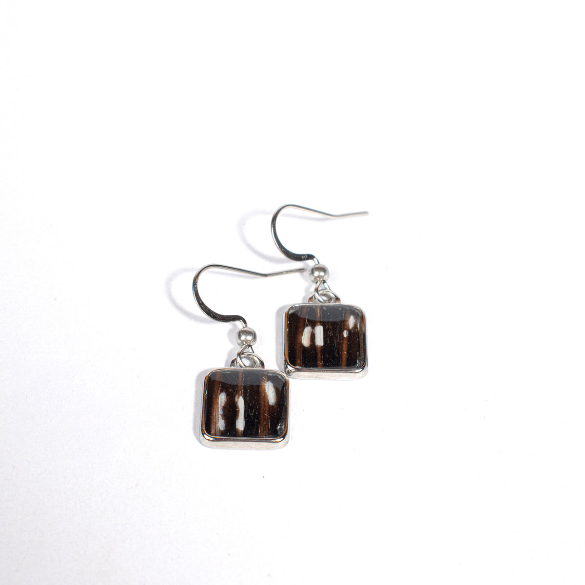 Square-shaped earrings with black and white, sometimes redish, design on a white background