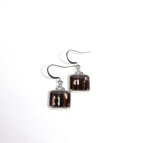 Square-shaped earrings with black and white, sometimes redish, design on a white background